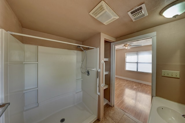 bathroom featuring hardwood / wood-style floors, vanity, a shower, ceiling fan, and a textured ceiling