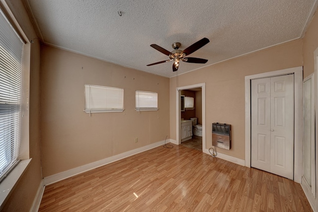 unfurnished bedroom featuring ceiling fan, light wood-type flooring, multiple windows, and heating unit