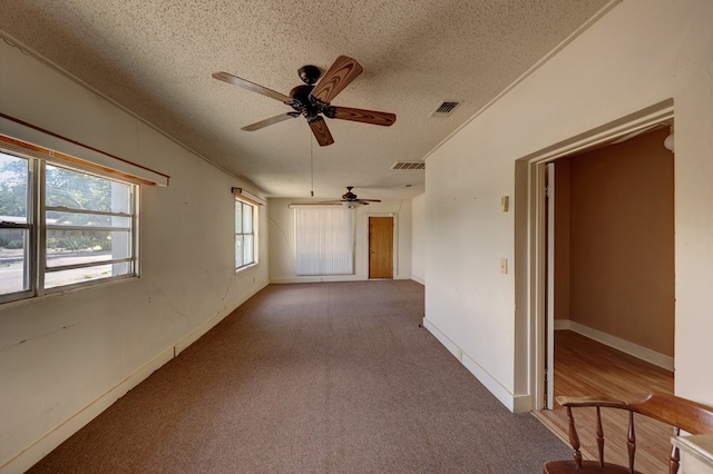 empty room featuring ceiling fan, carpet floors, and a textured ceiling