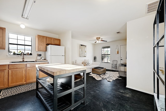 kitchen featuring ceiling fan, sink, and white refrigerator