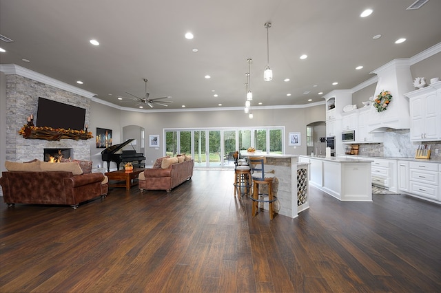 kitchen featuring dark hardwood / wood-style floors, a fireplace, a kitchen island, a kitchen bar, and white cabinetry