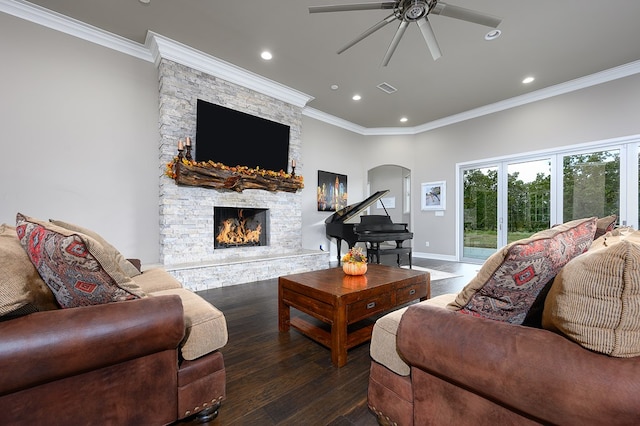 living room with ceiling fan, a stone fireplace, dark hardwood / wood-style flooring, and ornamental molding