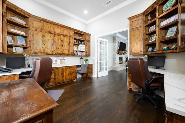 office space with a fireplace, dark hardwood / wood-style flooring, built in desk, and crown molding