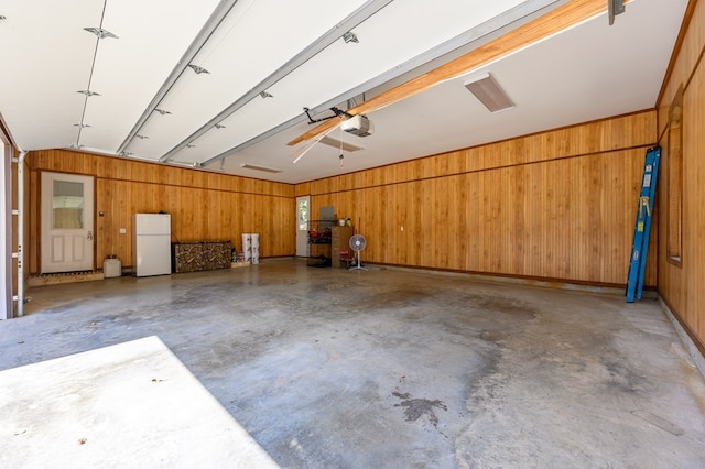 garage featuring white fridge, a garage door opener, and wooden walls