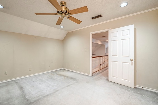 interior space with a textured ceiling, lofted ceiling, visible vents, and light carpet