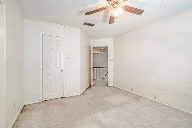 unfurnished bedroom with visible vents, light carpet, a textured ceiling, and ornamental molding