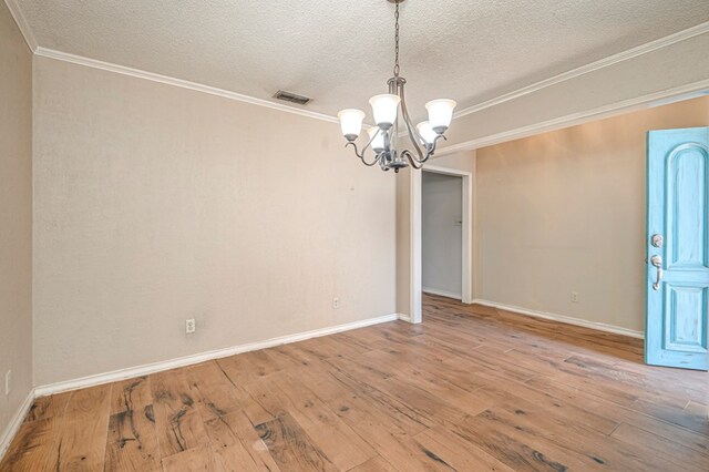 spare room with visible vents, wood-type flooring, a notable chandelier, and crown molding