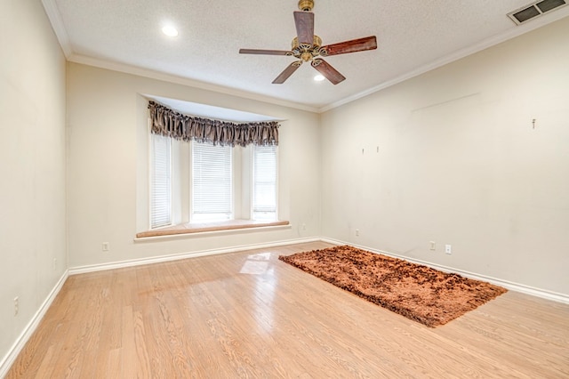 empty room featuring light wood-type flooring, visible vents, a textured ceiling, and crown molding