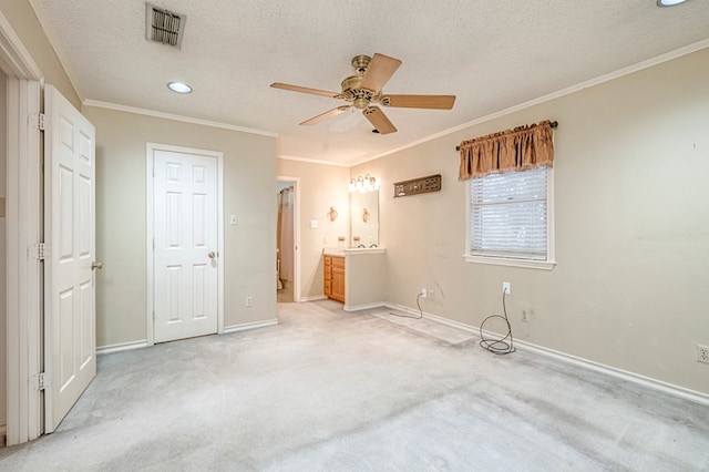 unfurnished bedroom featuring visible vents, a textured ceiling, ornamental molding, and light colored carpet