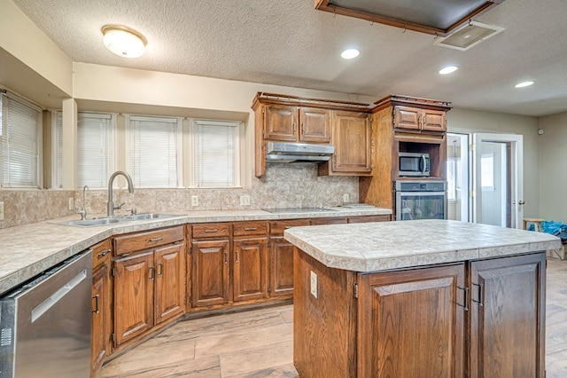 kitchen with visible vents, brown cabinets, under cabinet range hood, appliances with stainless steel finishes, and light countertops