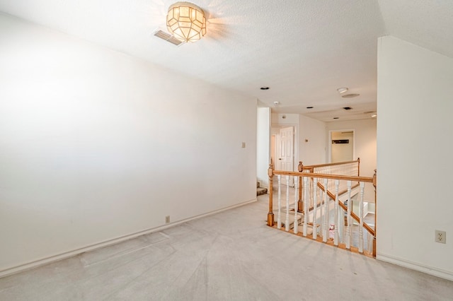 carpeted spare room featuring a textured ceiling and baseboards