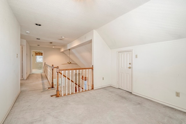 additional living space featuring baseboards, a textured ceiling, lofted ceiling, and carpet floors