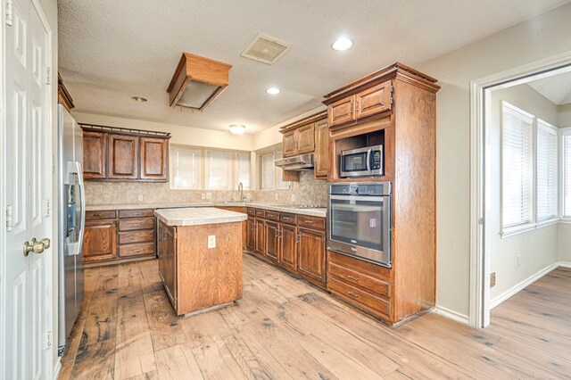 kitchen featuring a center island, stainless steel appliances, light countertops, and tasteful backsplash