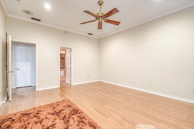 empty room featuring visible vents, light wood-style flooring, a ceiling fan, ornamental molding, and baseboards