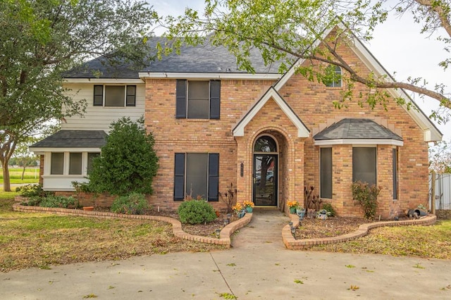 view of front of house with brick siding and roof with shingles