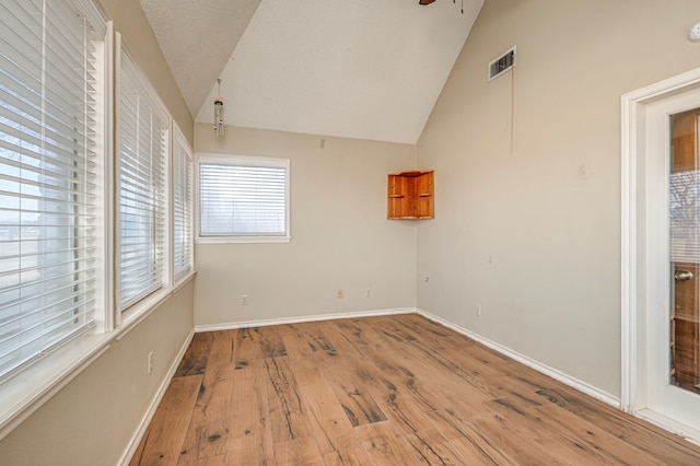 unfurnished room with baseboards, visible vents, ceiling fan, vaulted ceiling, and hardwood / wood-style flooring