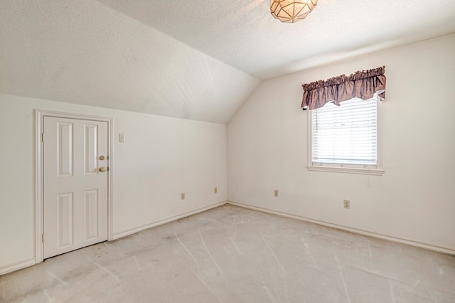 bonus room with vaulted ceiling, light colored carpet, and a textured ceiling