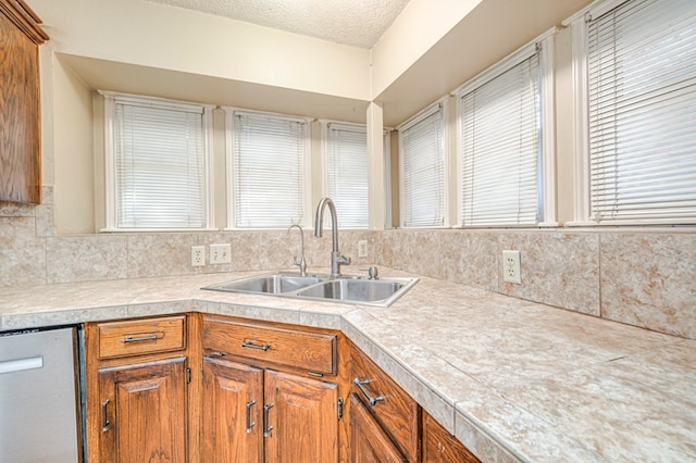 kitchen with brown cabinets, a wealth of natural light, and a sink