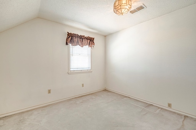 spare room with visible vents, a textured ceiling, carpet flooring, and vaulted ceiling