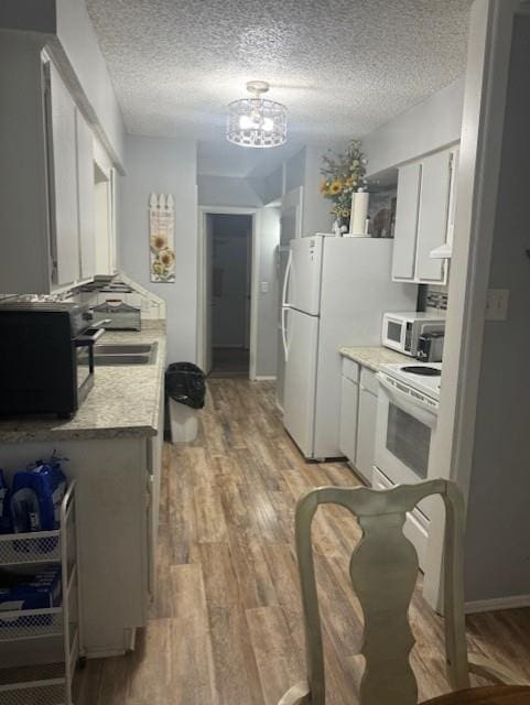 kitchen with a textured ceiling, sink, white cabinets, and white appliances