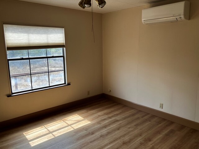 unfurnished room with light wood-type flooring and a wall unit AC