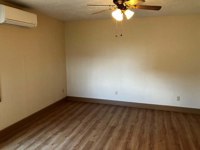 unfurnished room with a wall mounted air conditioner, wood-type flooring, a textured ceiling, and ceiling fan