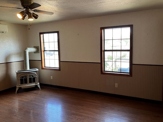 spare room with a wood stove, wooden walls, dark hardwood / wood-style flooring, and a textured ceiling