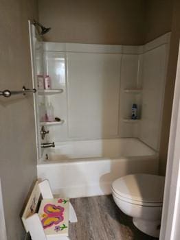 bathroom with shower / bathing tub combination, toilet, and wood-type flooring