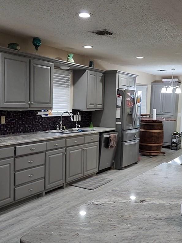 kitchen with gray cabinetry, sink, stainless steel appliances, a textured ceiling, and light wood-type flooring