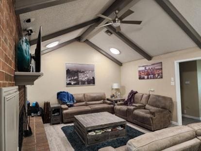 cinema with vaulted ceiling with beams, ceiling fan, light hardwood / wood-style flooring, and a brick fireplace