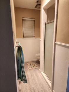 bathroom with toilet, hardwood / wood-style floors, and walk in shower