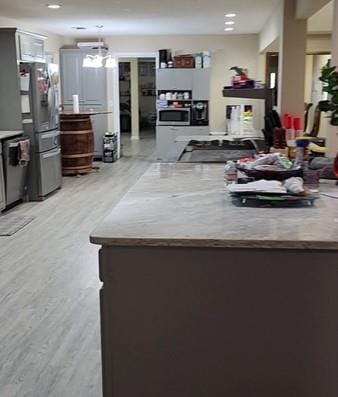 kitchen with kitchen peninsula, a chandelier, stainless steel appliances, and light wood-type flooring