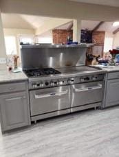 kitchen with light wood-type flooring, high end stove, and gray cabinetry