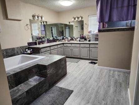 bathroom featuring hardwood / wood-style floors, vanity, a bath, and a textured ceiling