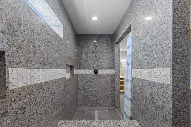 full bath with tiled shower, tile patterned flooring, and tile walls