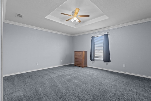 empty room with a tray ceiling, carpet, crown molding, ceiling fan, and baseboards