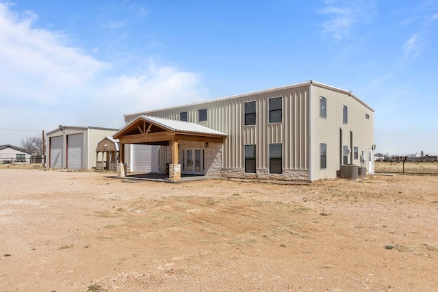 back of house featuring an outbuilding, stone siding, a detached garage, and french doors