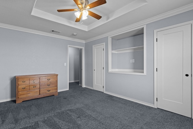 unfurnished bedroom featuring dark colored carpet, a raised ceiling, and baseboards