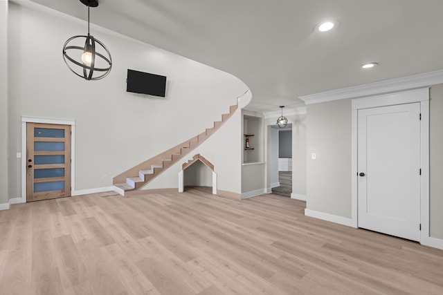 unfurnished living room with light wood-style floors, stairs, baseboards, and crown molding