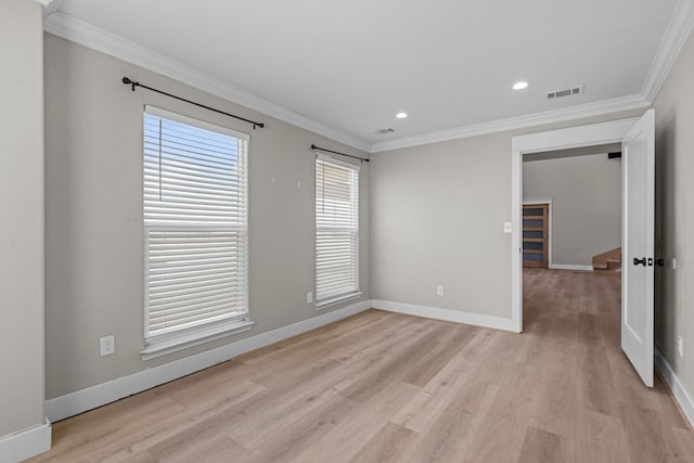 unfurnished room with light wood-style flooring, visible vents, baseboards, and ornamental molding