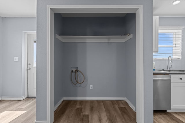 laundry area with wood finished floors, a sink, and baseboards