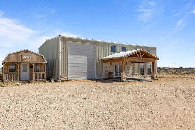 view of front of property with stone siding, an outbuilding, and french doors