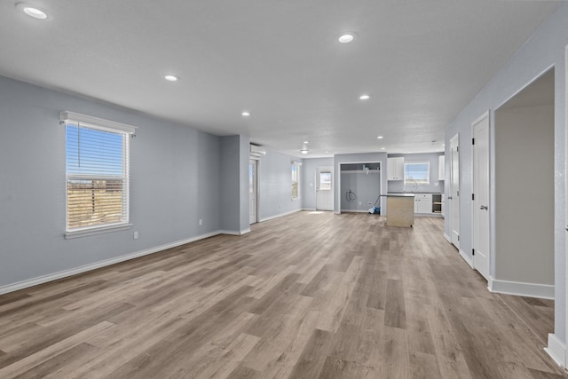 unfurnished living room with baseboards, light wood-type flooring, and recessed lighting