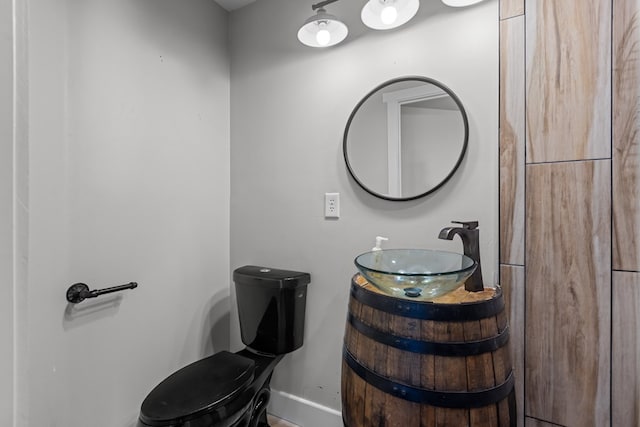 half bath featuring vanity, toilet, and baseboards