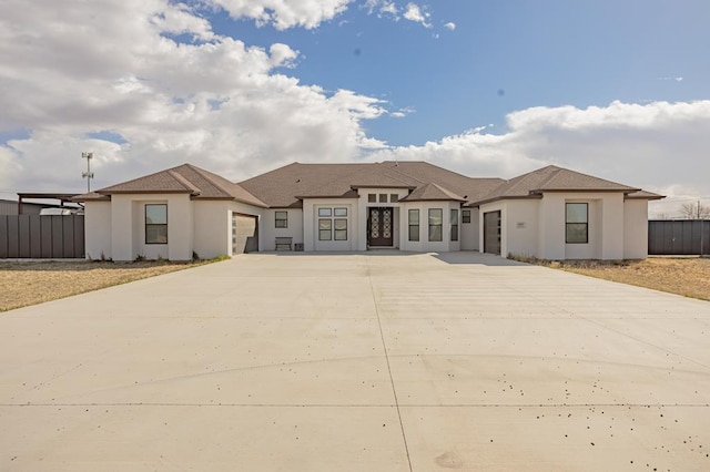 view of front of home featuring stucco siding, driveway, an attached garage, and fence