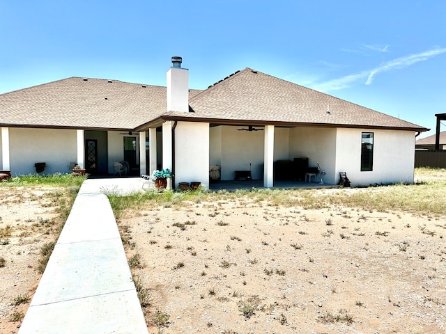 rear view of house featuring stucco siding, a patio area, roof with shingles, and a chimney