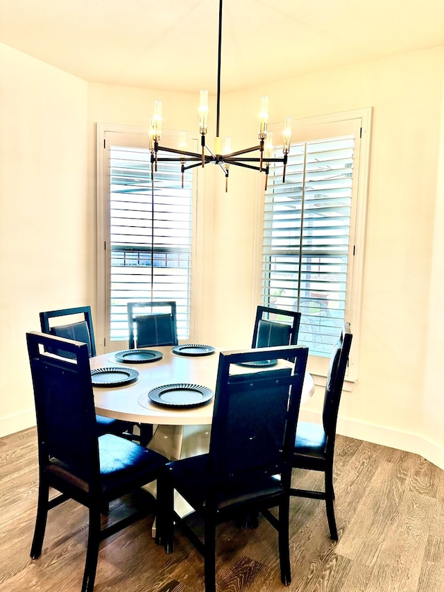 dining space with a chandelier, baseboards, and wood finished floors