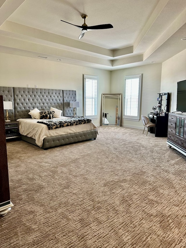 bedroom with ceiling fan, a tray ceiling, and carpet floors