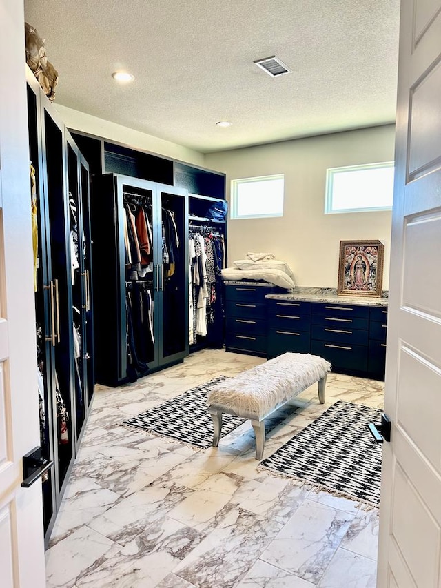 spacious closet featuring visible vents and marble finish floor