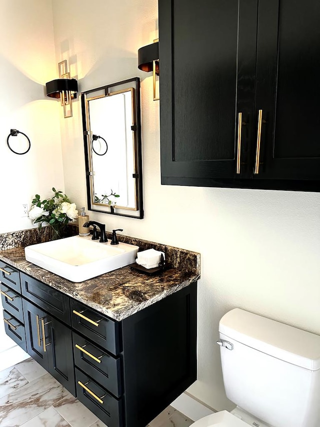 half bath with vanity, toilet, and marble finish floor